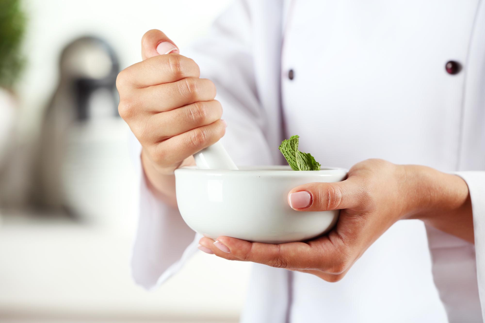 Hands seasoning a bowl with herbs