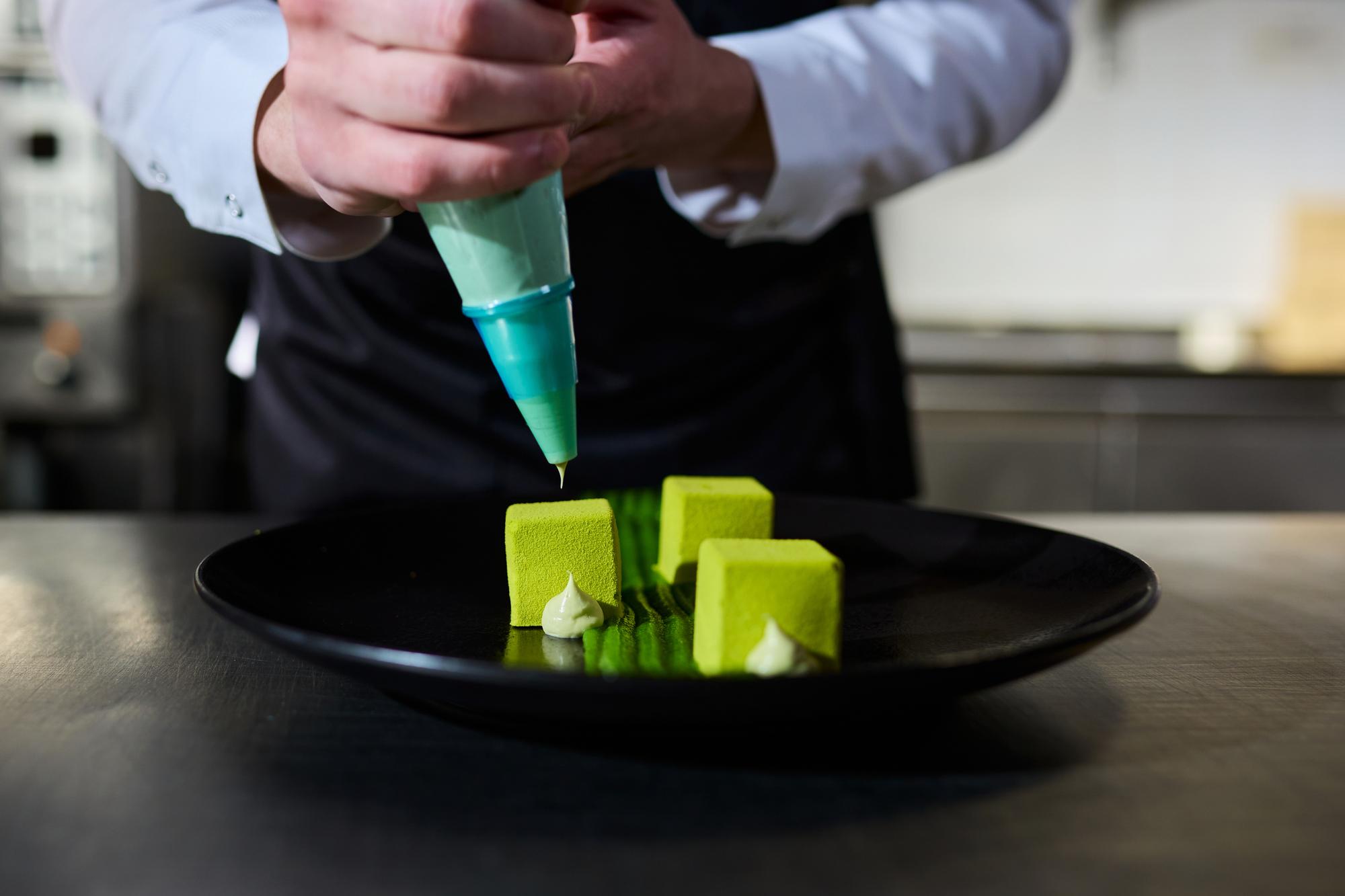 Chef preparing a plated modern dish with neon kitchen